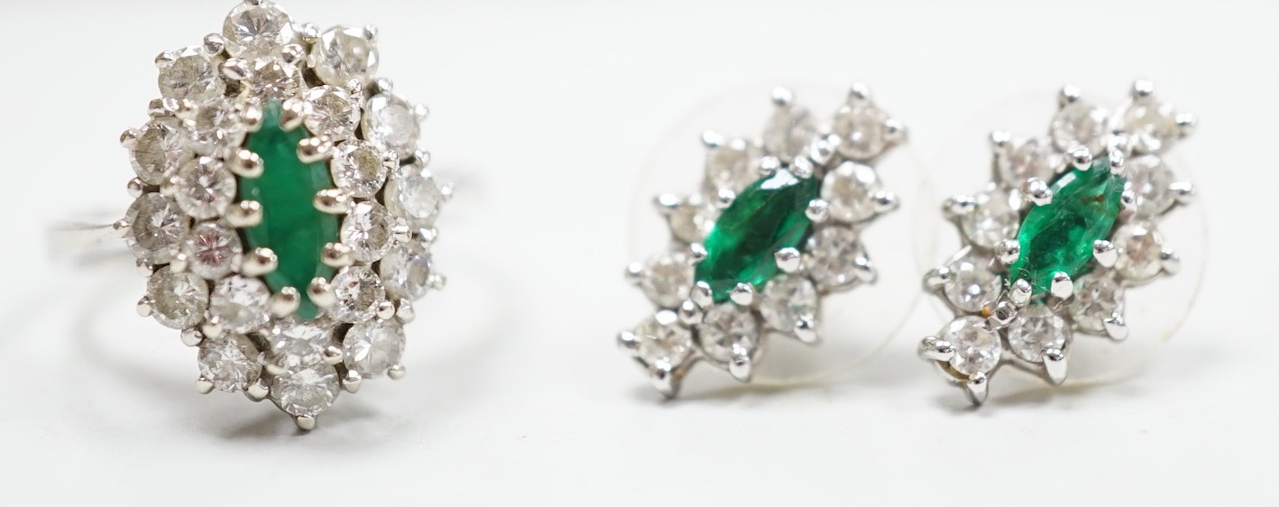 A modern 18ct white gold, emerald and diamond set oval cluster ring, size K/L and a pair of matching earrings, gross weight 7.2 grams.